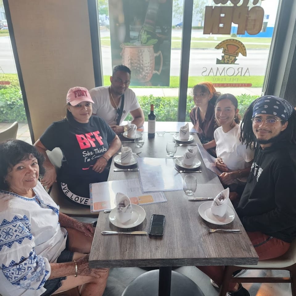 Six people, three men and three women, sitting around a table at Aromas del Peru restaurant.