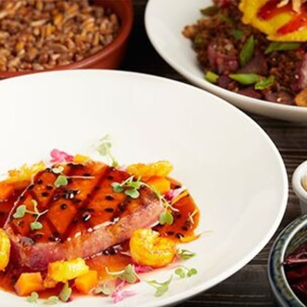 Peruvian dish with seared tuna, passion fruit sauce, and microgreens, alongside other Peruvian plates.