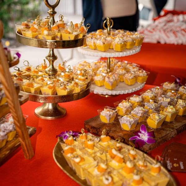 Dessert table with tiered stands of mango and ube panna cotta, garnished with orchids.