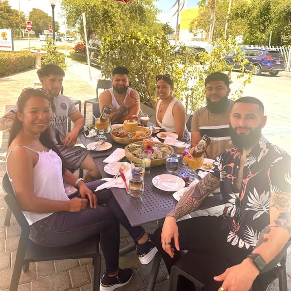 Six friends enjoying Peruvian food and drinks at an outdoor table at Aromas del Peru.