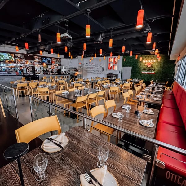 Aromas del Peru restaurant interior with set tables, red booth seating, a bar, and a green wall.