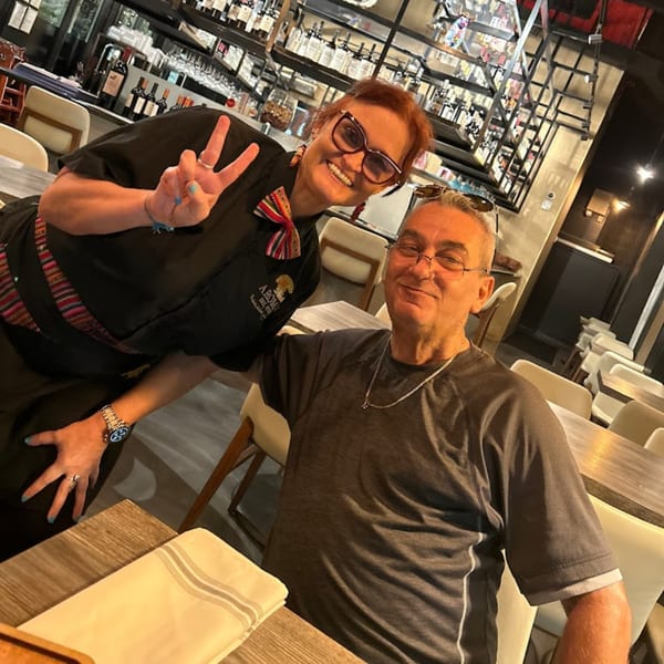 A smiling Aromas del Peru staff member and a male customer pose for a photo.