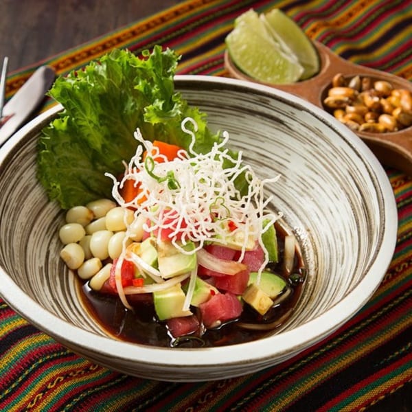Peruvian ceviche with tuna, avocado, corn, and lettuce, served with toasted corn and lime.