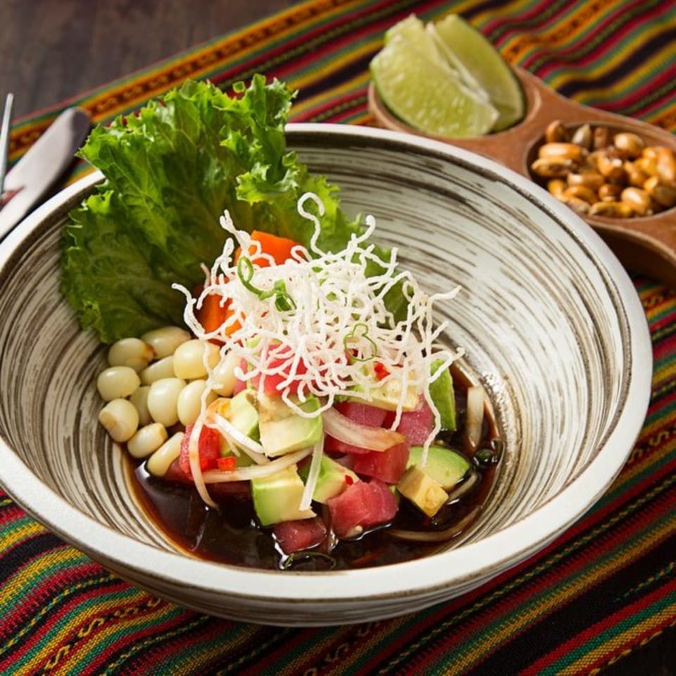 Peruvian ceviche with tuna, avocado, corn, and lettuce, served with toasted corn and lime.