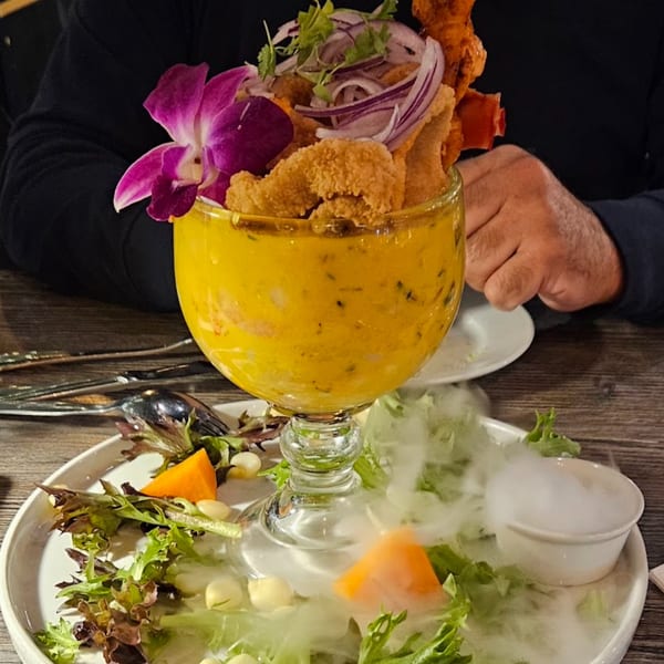 Aromas del Peru's Peruvian ceviche in a large glass, garnished with a purple orchid and dry ice.