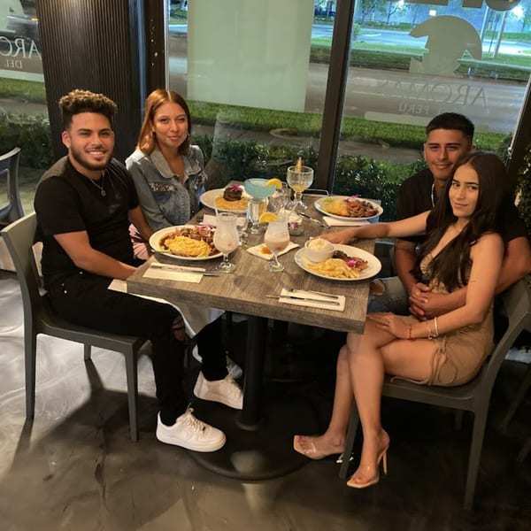 Four young adults enjoying Peruvian dishes and drinks at a table in Aromas del Peru restaurant.