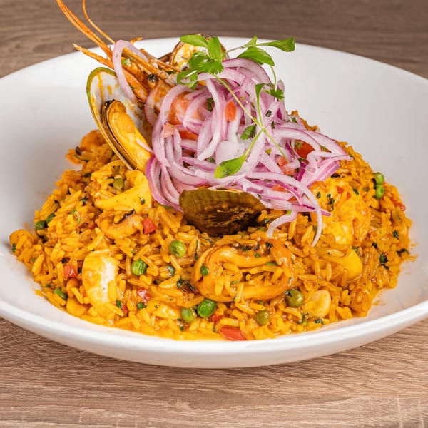 Peruvian Arroz con Mariscos, a seafood rice dish, garnished with red onions and cilantro.