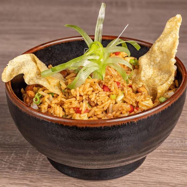 Peruvian fried rice (Arroz Chaufa) in a dark bowl, garnished with green onions and crispy wontons.